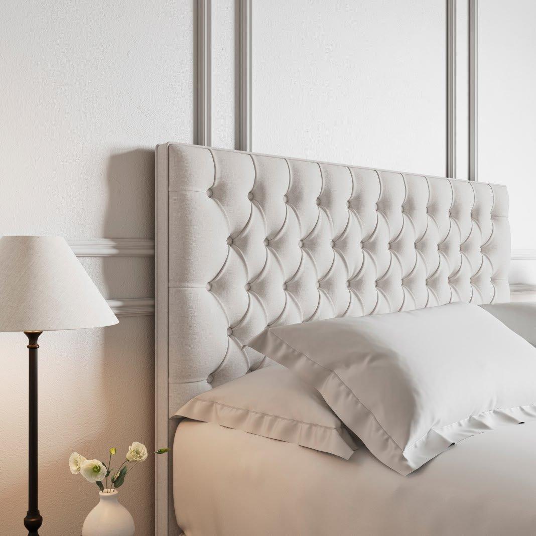 a bed with white headboard and pillows and a nightstand with a lamp