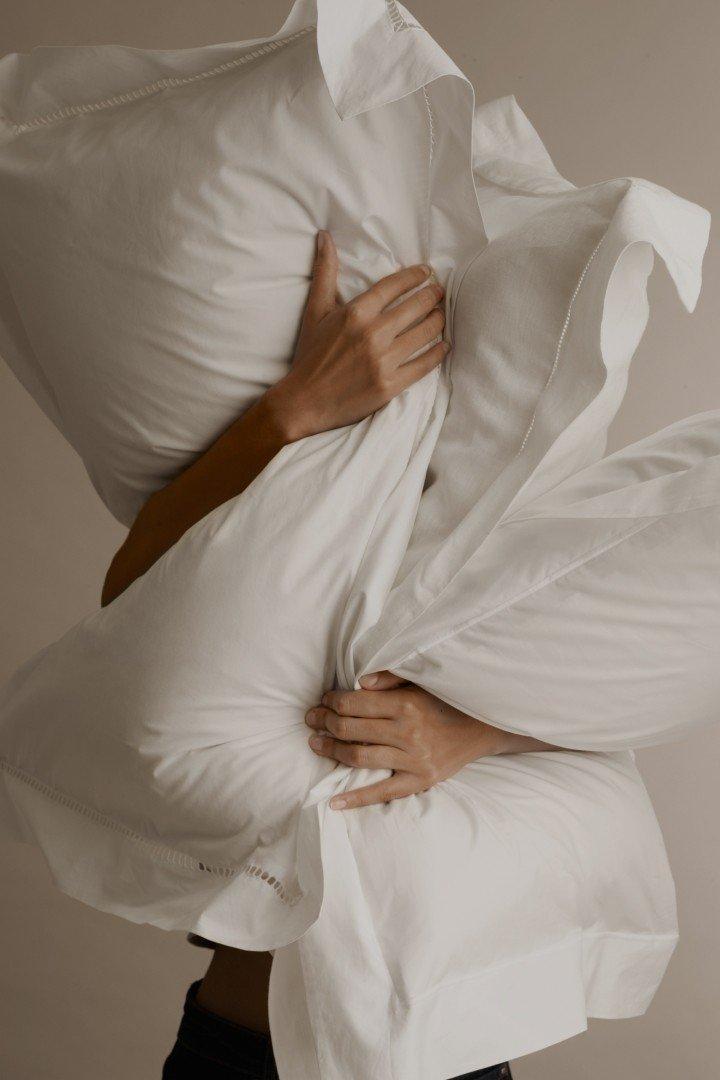 a bed with a white comforter and a plant on top of it