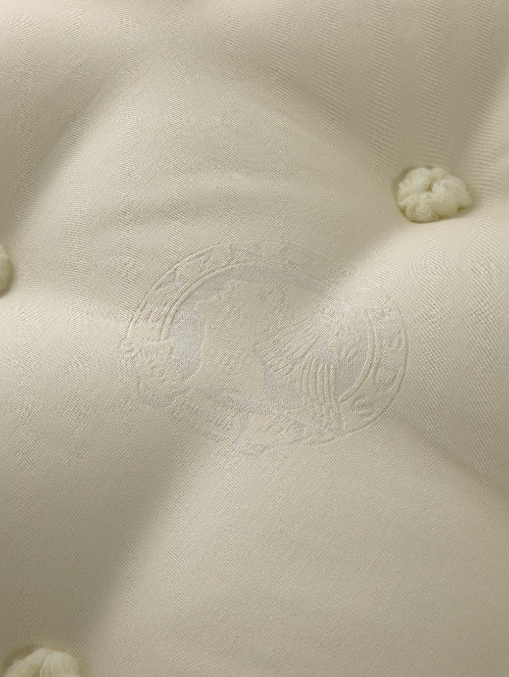 a close up of a mattress with a white cover and a white button