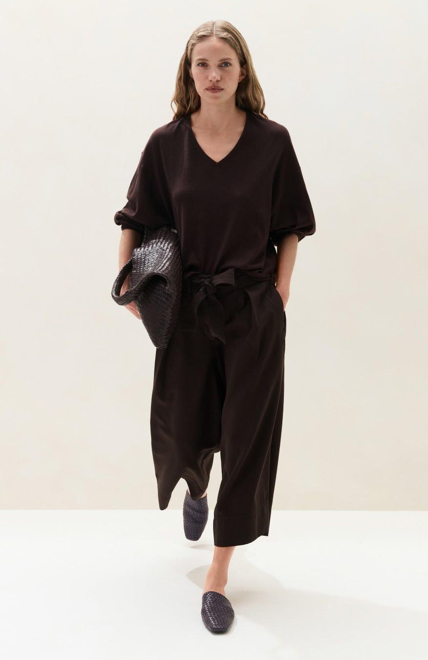 a woman in a brown jumpsuit walking with a handbag