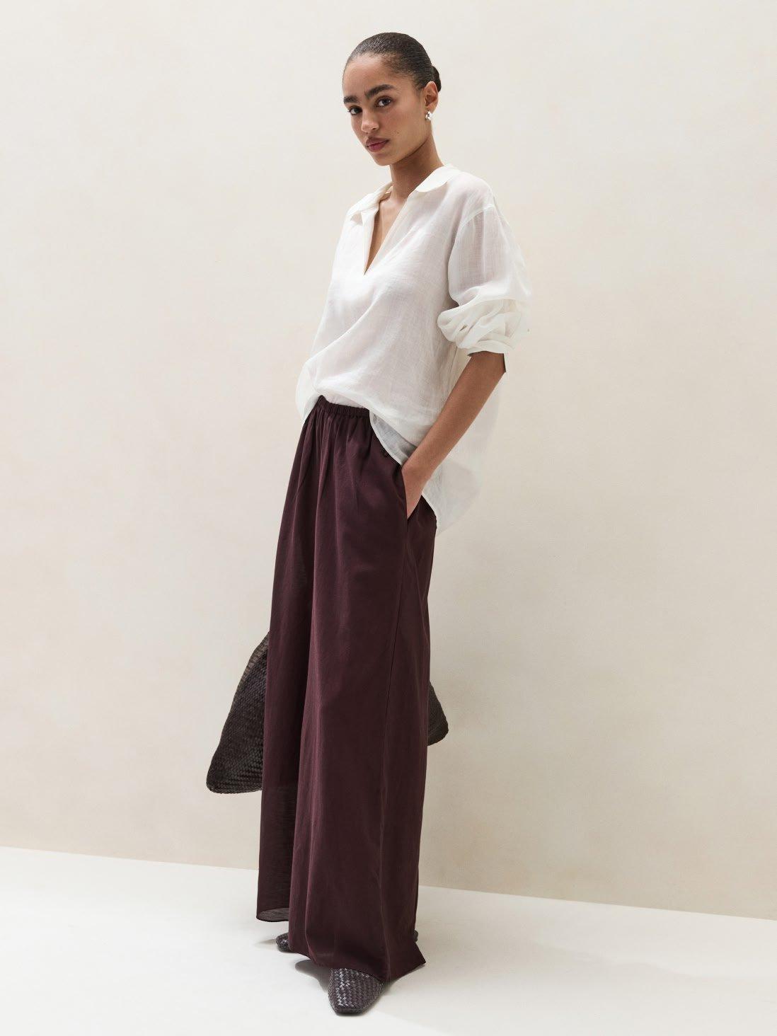 a woman in a white shirt and maroon pants