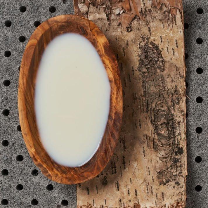 a wooden bowl with a white substance in it next to a piece of wood