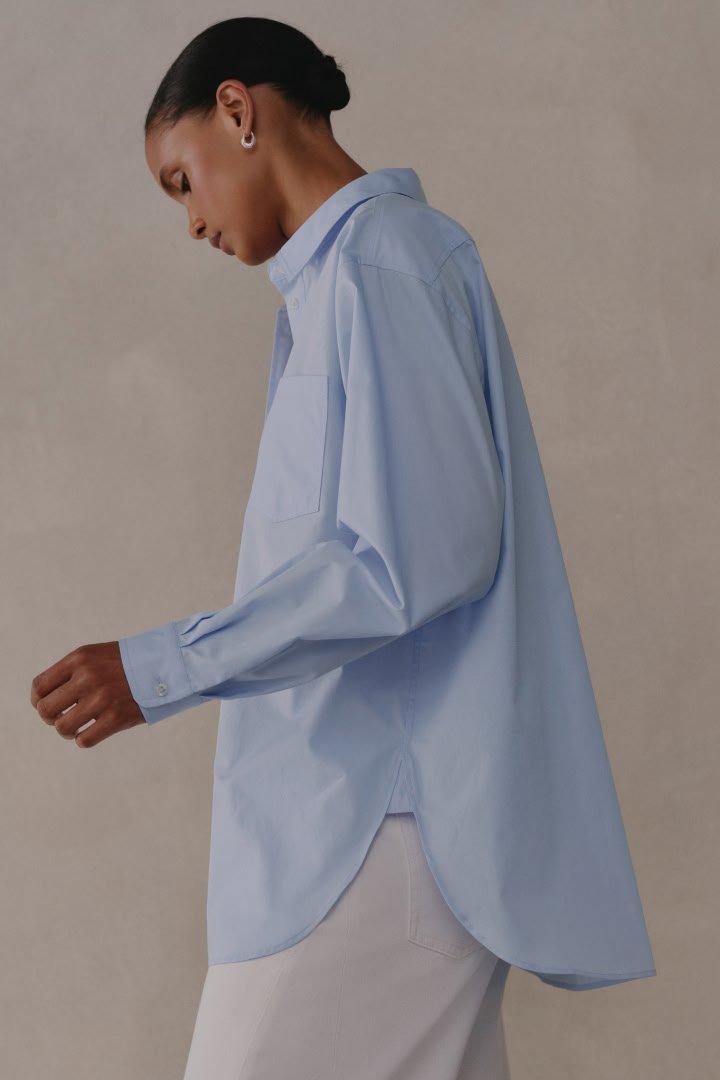 a woman in a blue shirt and white pants walking