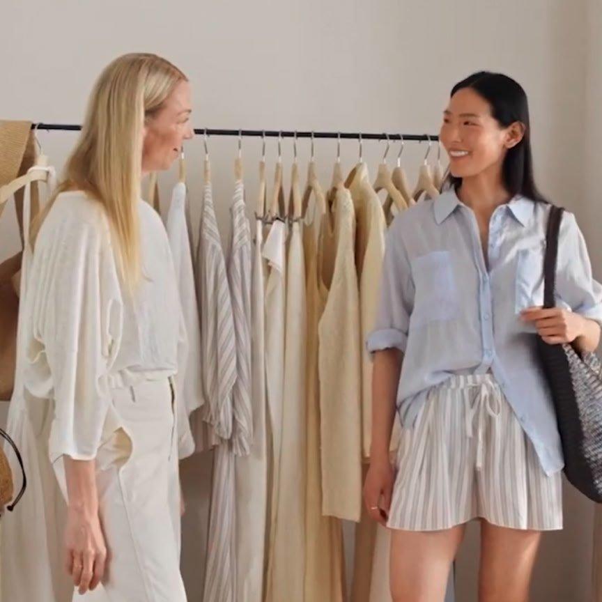 two women talking in front of a rack of clothes