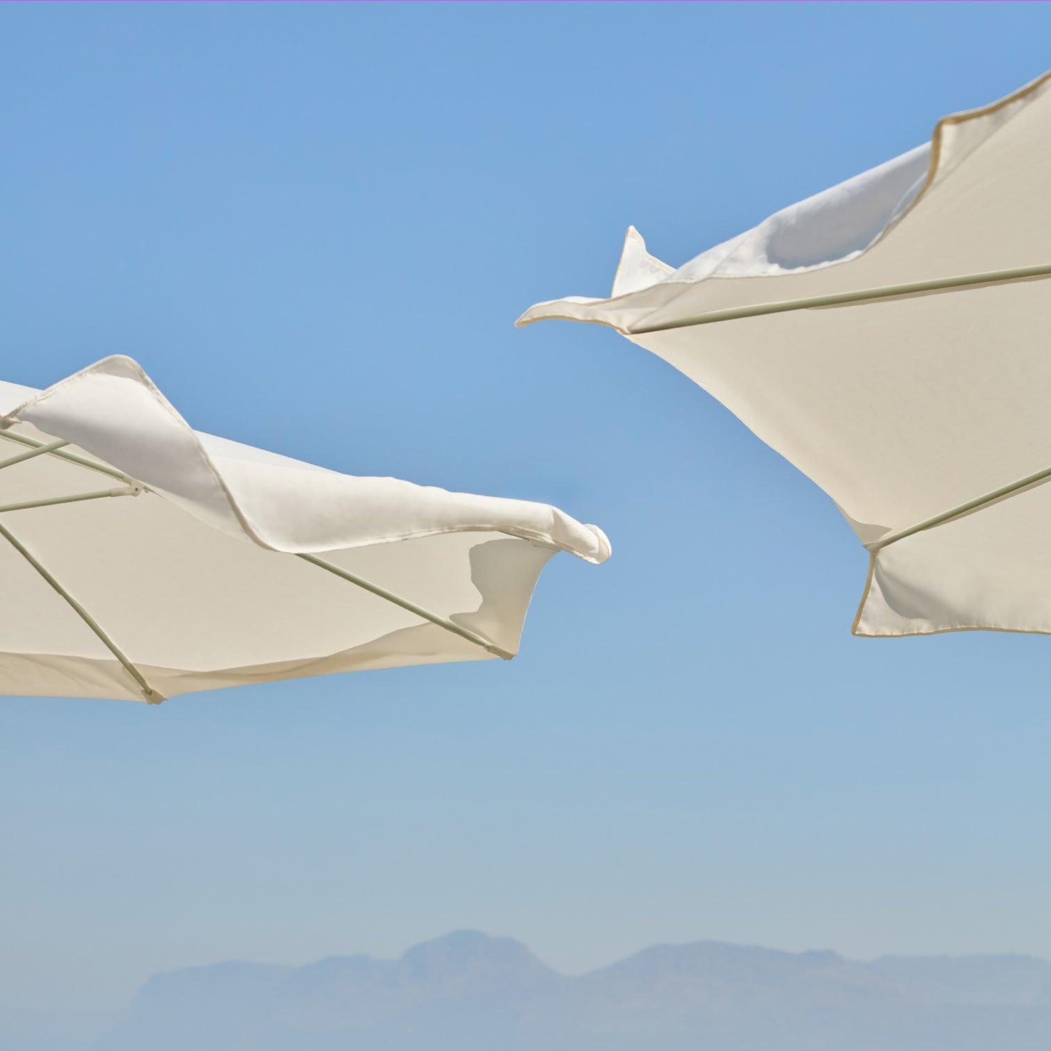 two white umbrellas are open in the sky with a mountain in the background