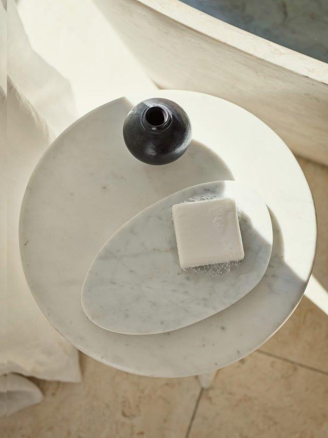 a close up of a white marble table with a soap and a bottle of water