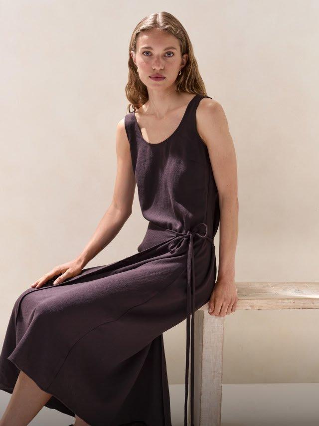 a woman sitting on a bench wearing a purple dress