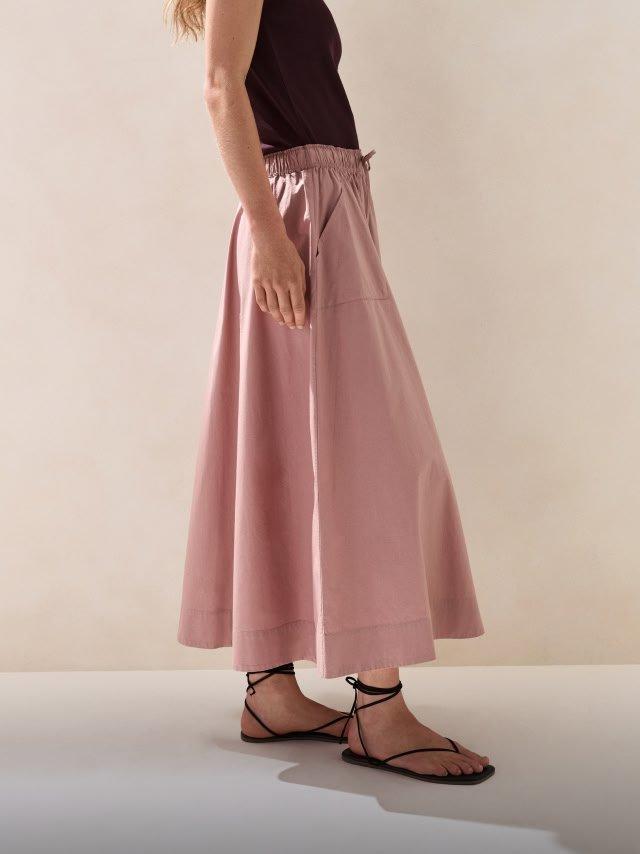 a woman in a black top and pink skirt