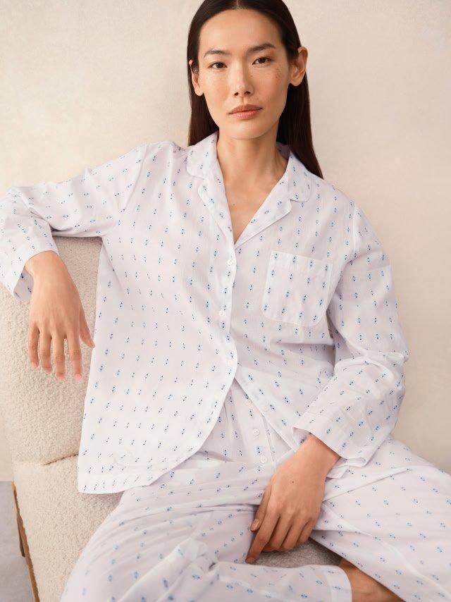 a woman in a white pajama top and pants sitting on a chair