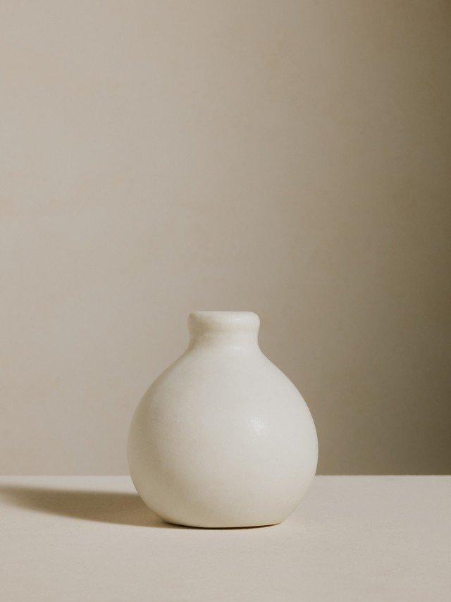 a white vase sitting on a table with a white background