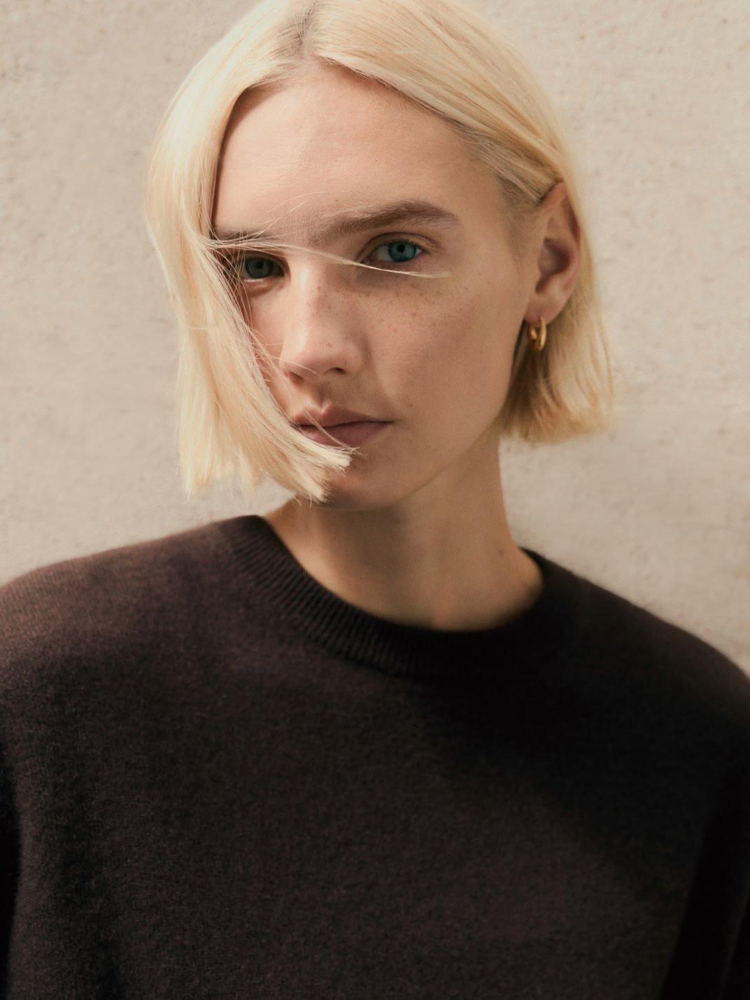 a woman with blonde hair wearing a black shirt and yellow dot