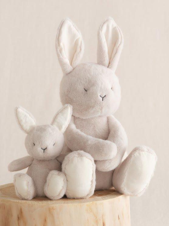 a couple of two stuffed rabbits sitting on a stump
