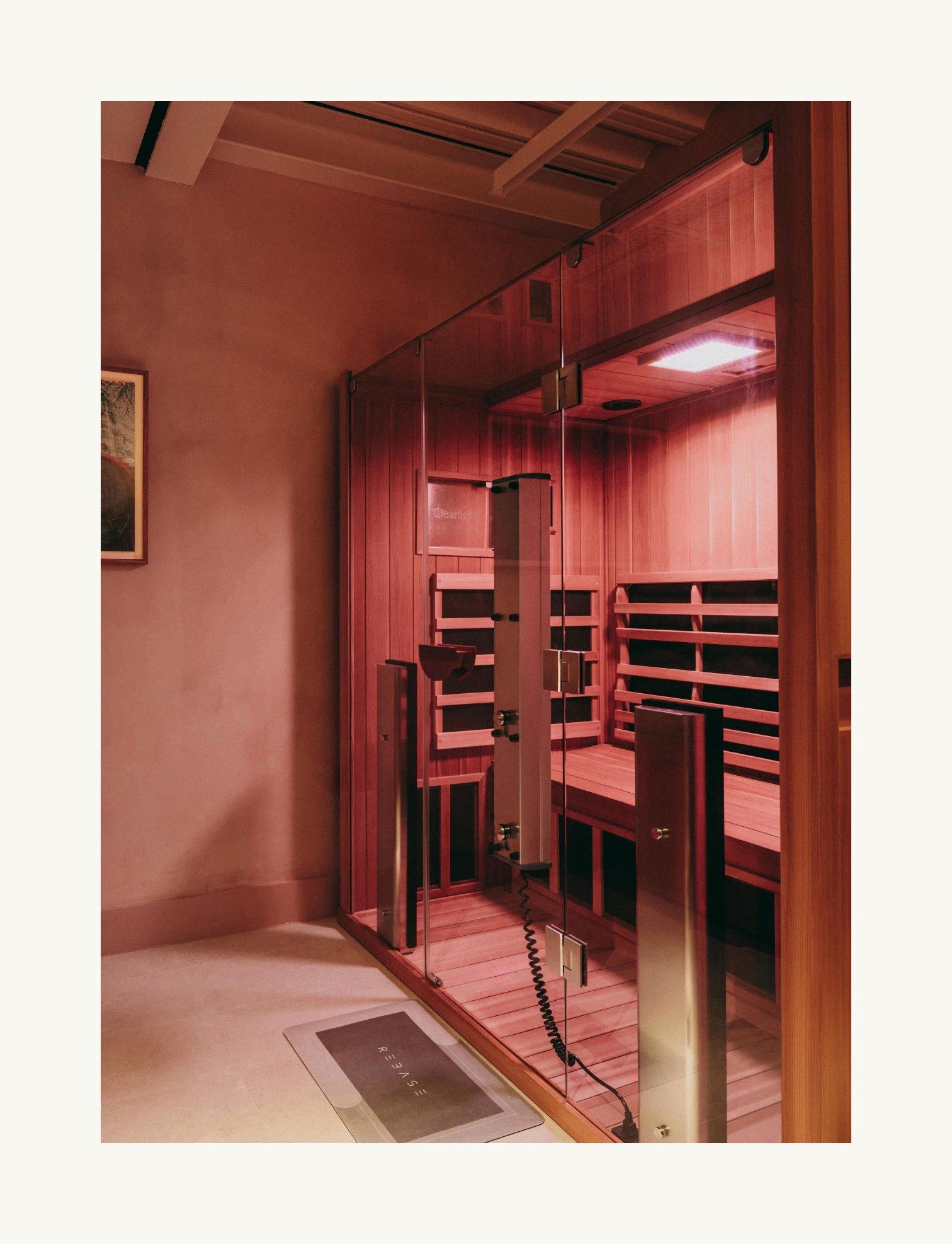 a sauna room with a glass door and a wooden bench