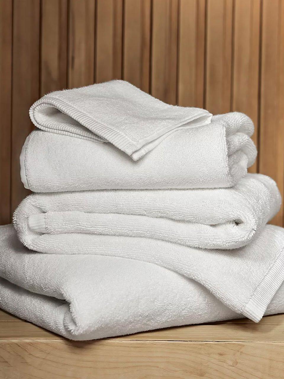 a stack of white towels on a wooden surface in a bathroom