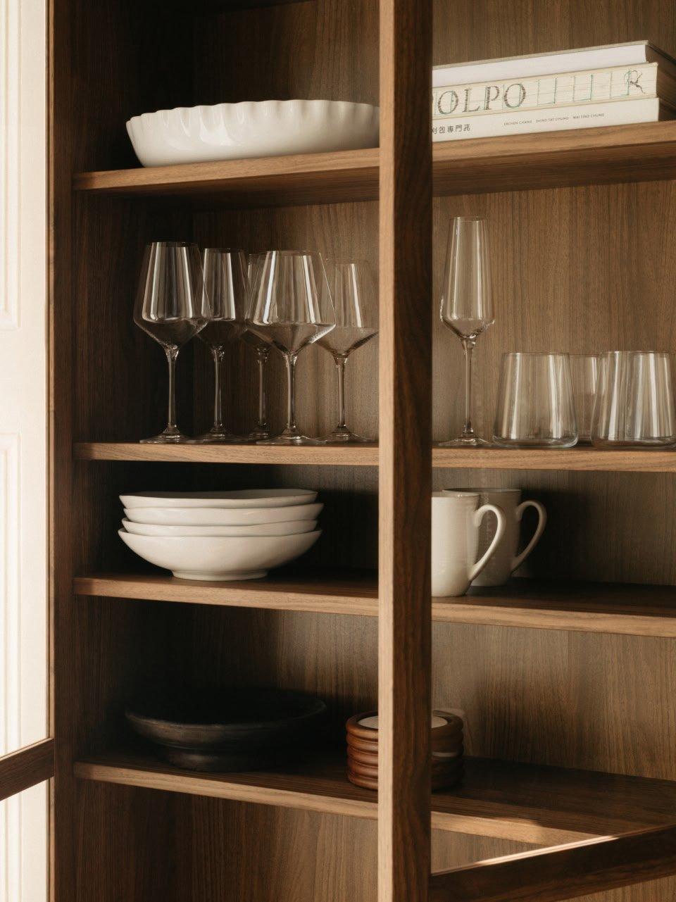 a wooden cabinet with glasses, plates and bowls on shelves
