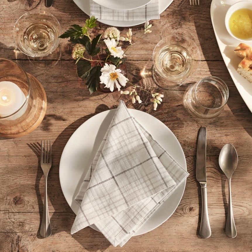 a table with a white plate, silverware, and napkins