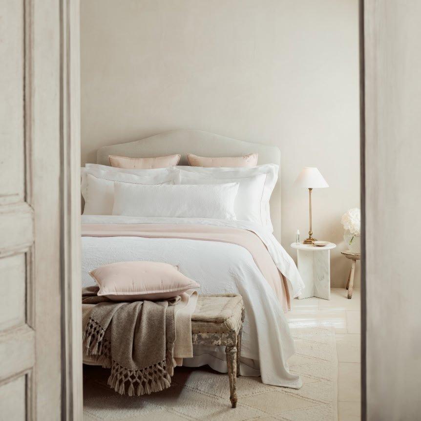 a bed with a white comforter and pillows in a bedroom