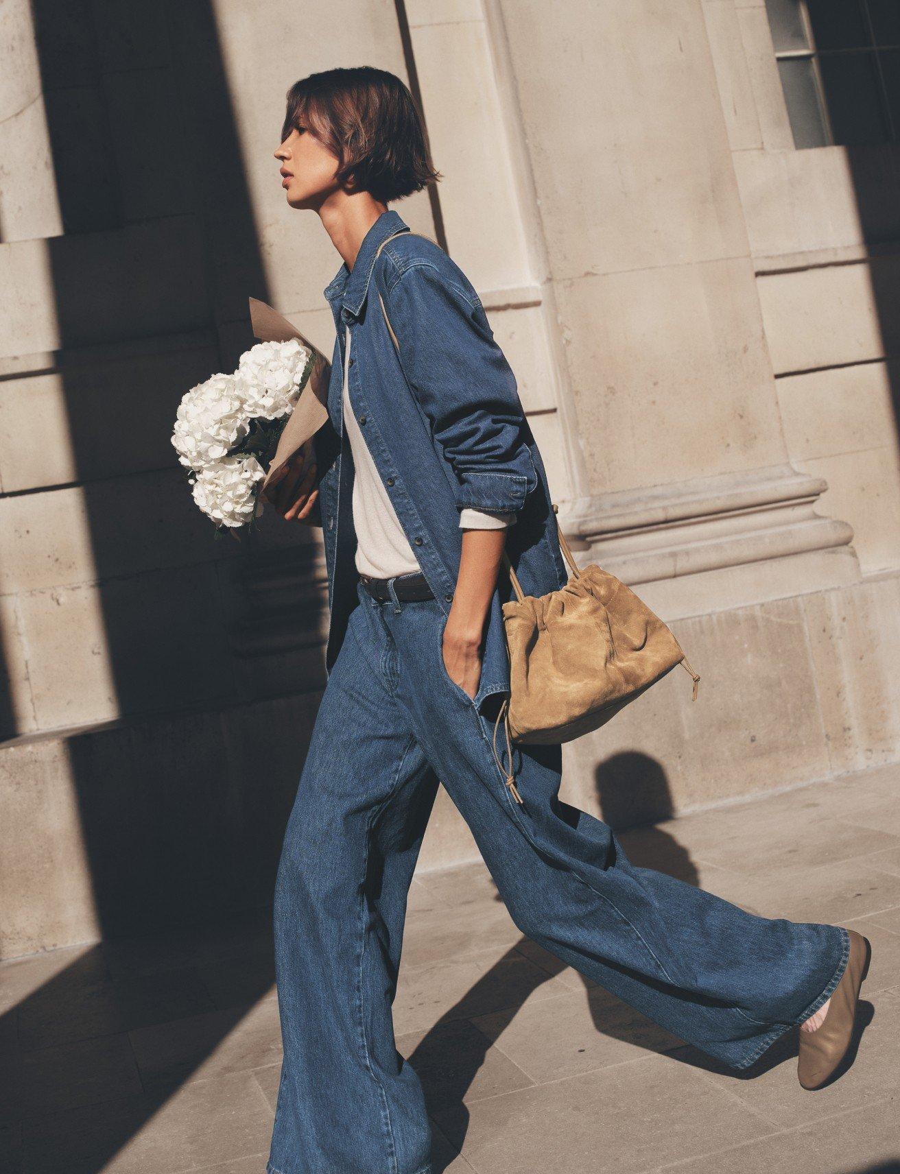 a woman walking down a street with a bouquet of flowers