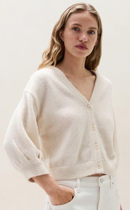 a woman in white pants and a white cardigan sweater