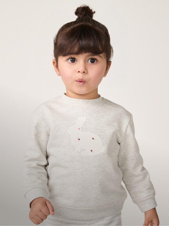 a little girl in a white sweatshirt and black pants