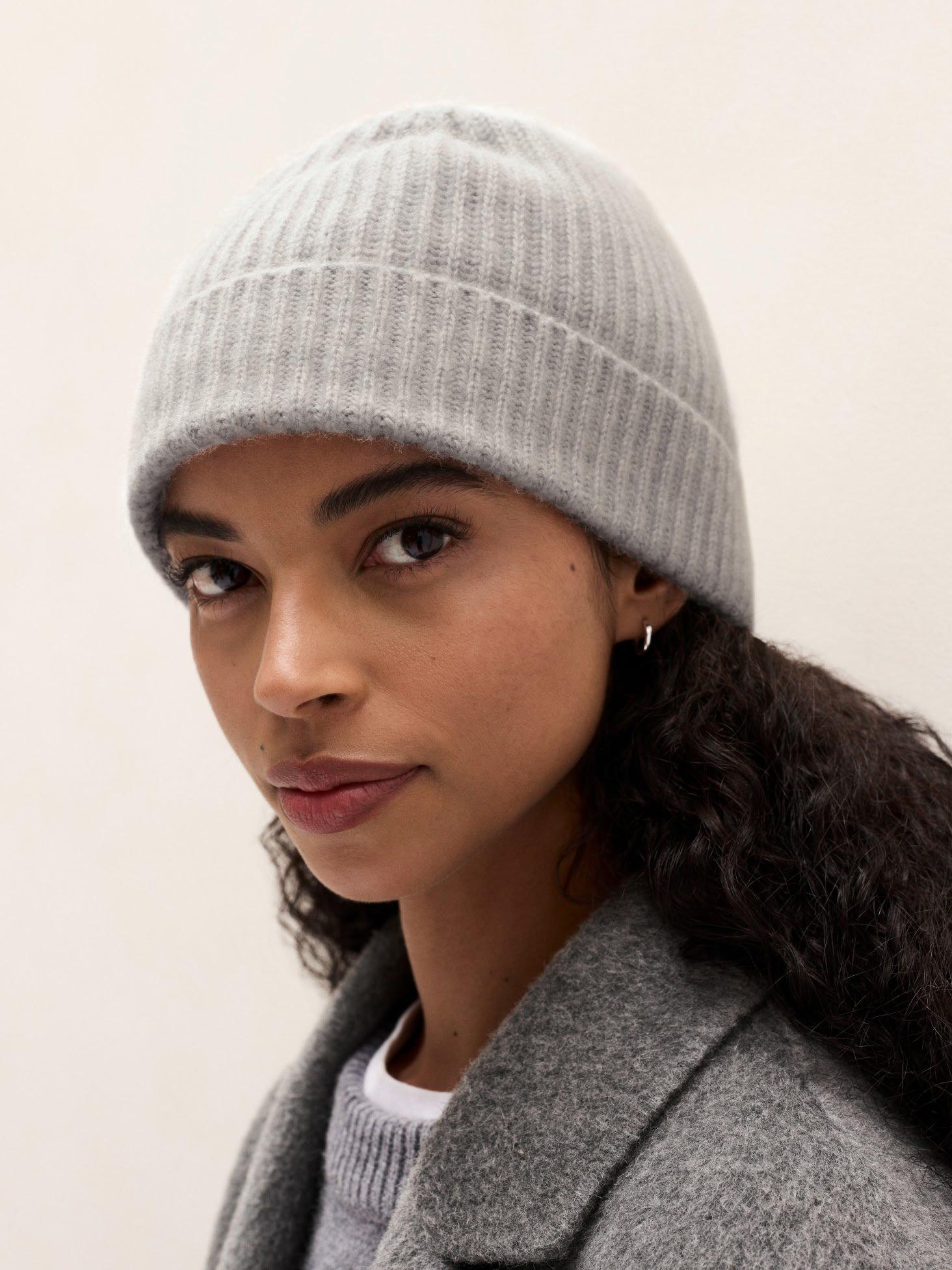 a woman with long curly hair wearing a gray hat