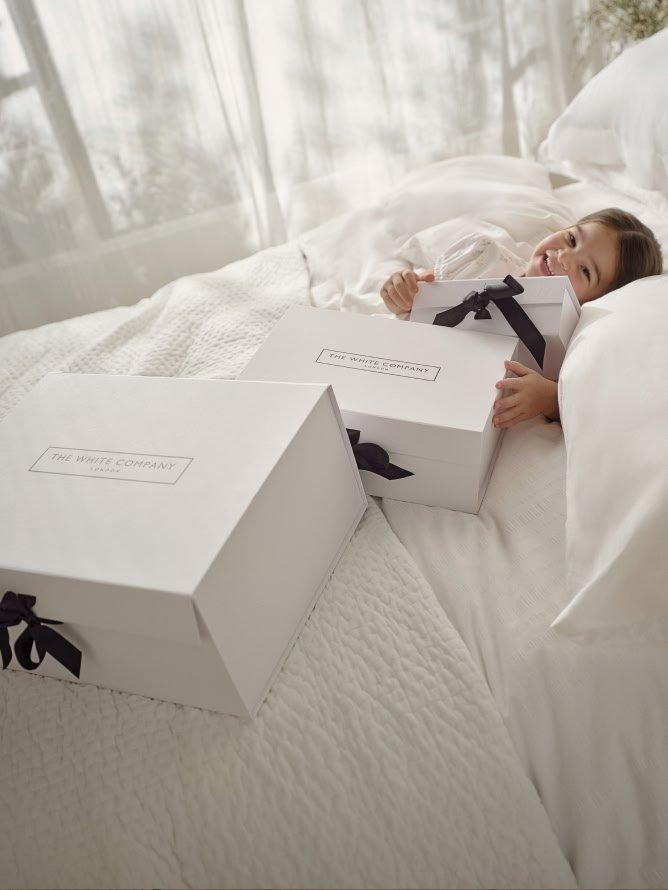 a little girl laying in bed with two boxes on top of her