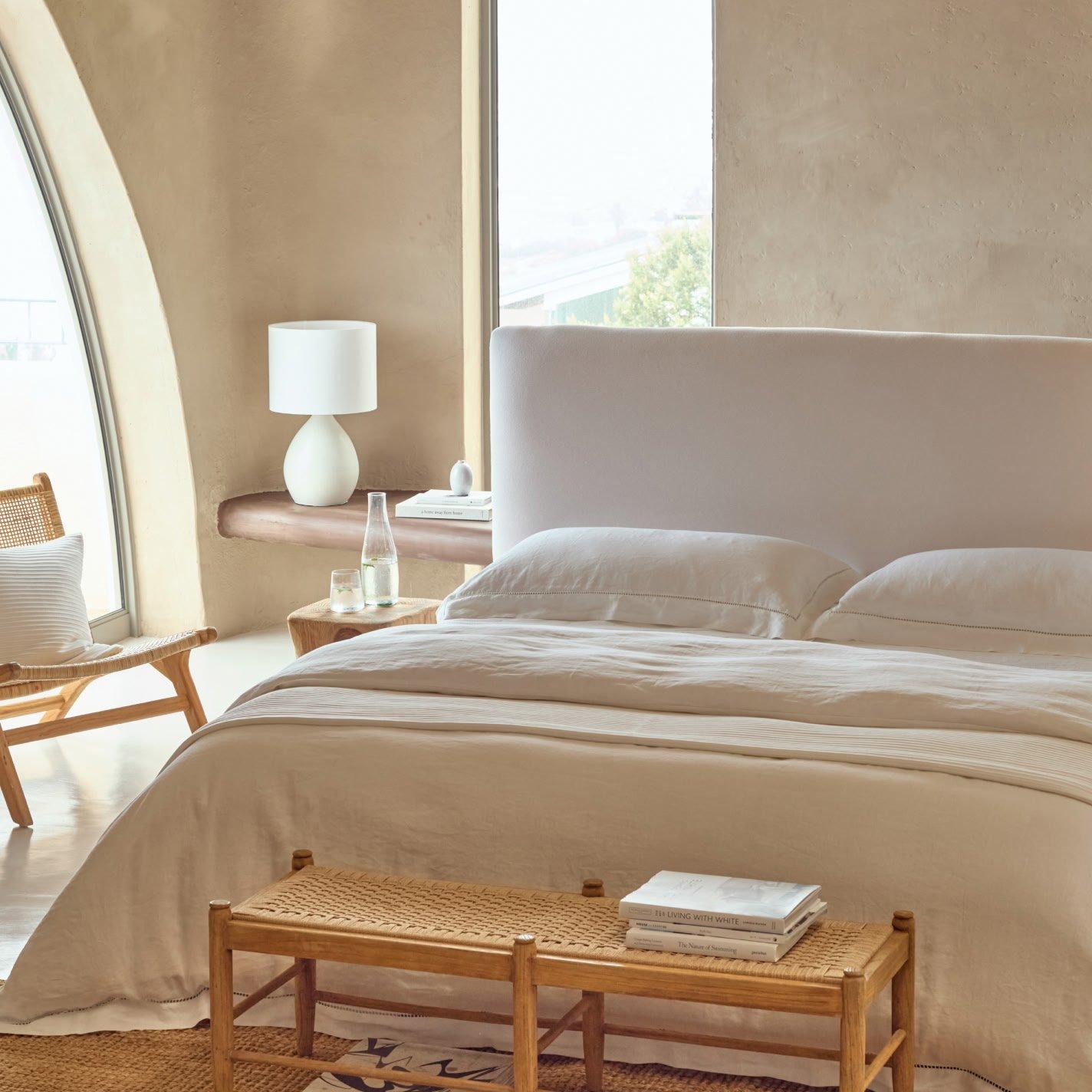 a bed with white sheets and pillows in a bedroom